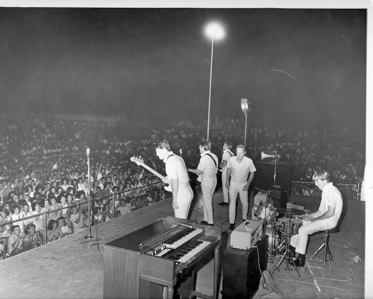 Cómo Brian Wilson, compositor visual en el libro Beach, cambió la historia de la música 2 Chicos en el escenario ante una gran multitud.