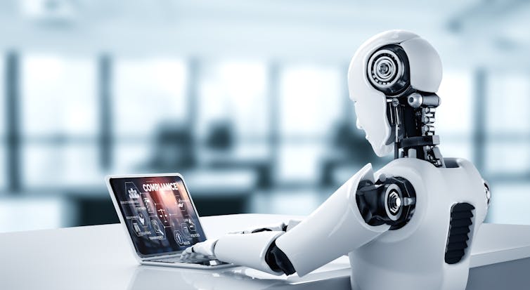 robot at work desk with laptop