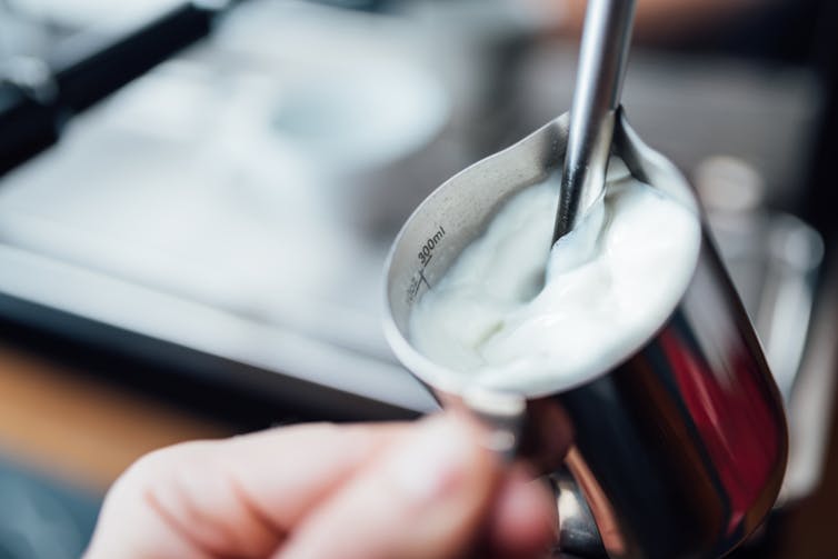 Close-up of a stainless steel pitcher with milk foam.
