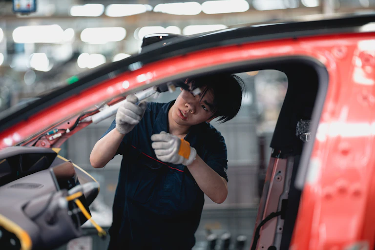 Un ouvrier effectue des réglages sur un véhicule dans une usine.