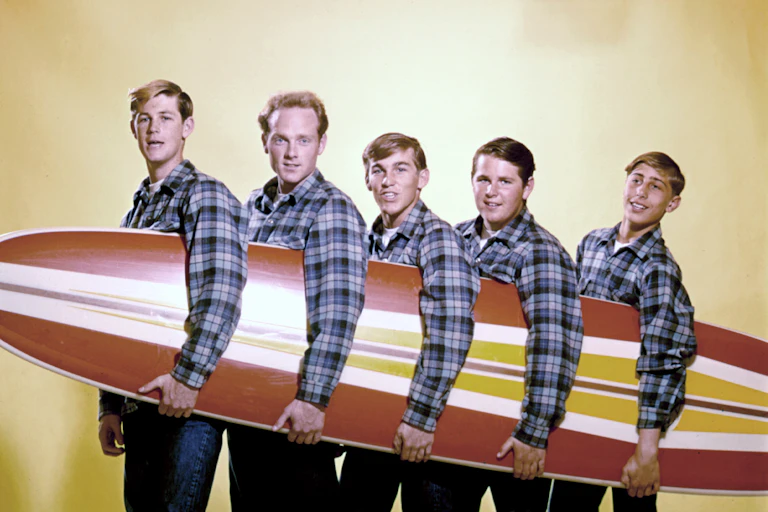 Cinq hommes tiennent une planche de surf