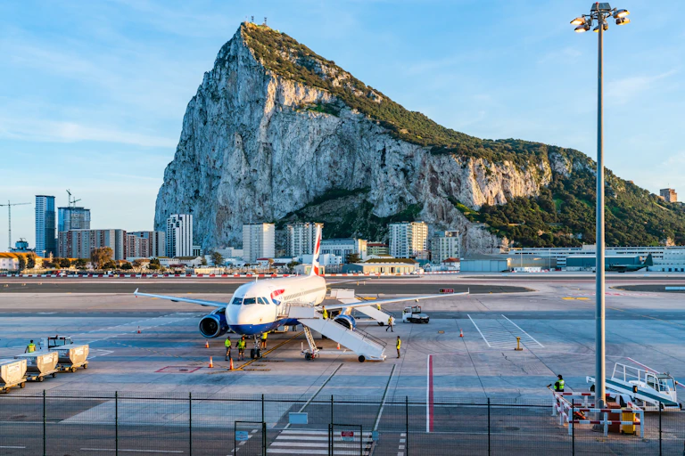 Un avión en primer plano y, al fondo, el Peñón de Gibraltar