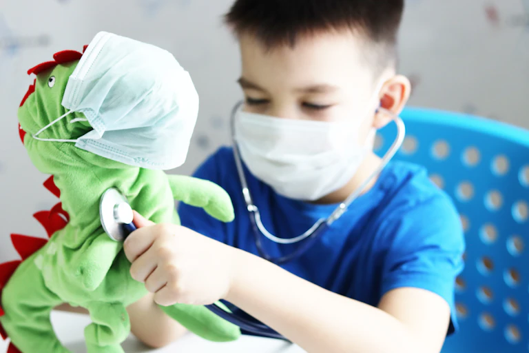 Young boy uses stethoscope on toy dinosaur.