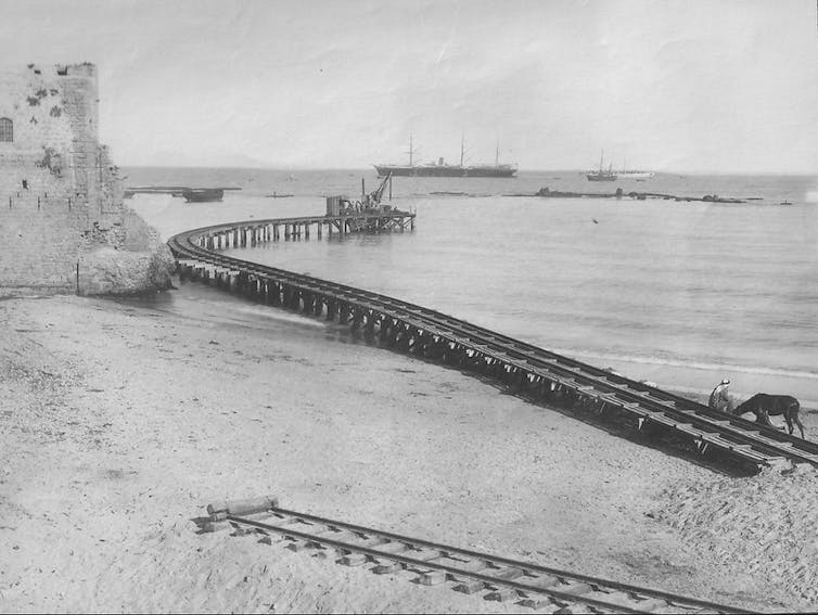 Fotografía en blanco y negro de una vía del tren adentrándose en el mar.