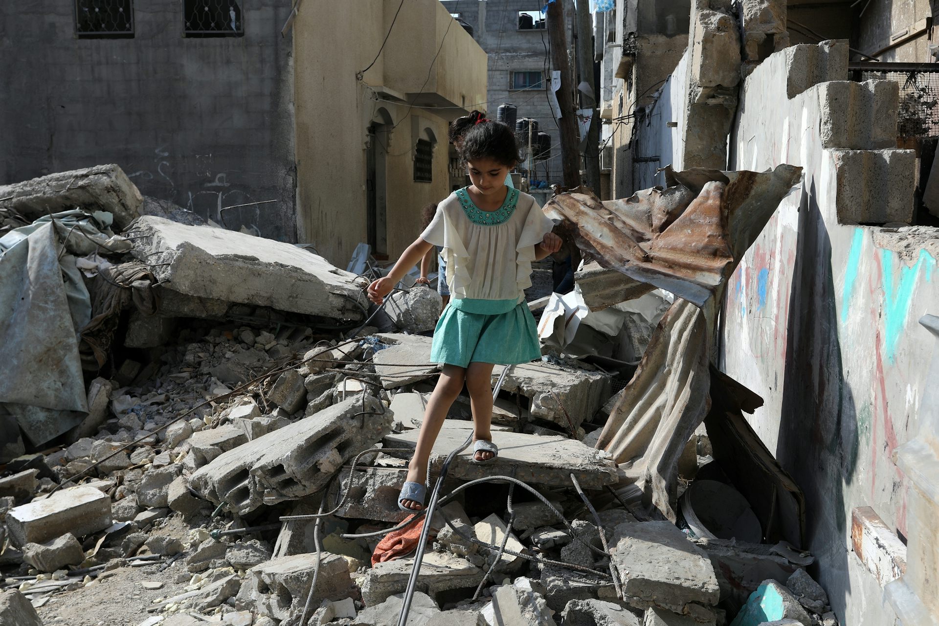 Une petite fille marche prudemment sur des gravats, dans une zone de conflit