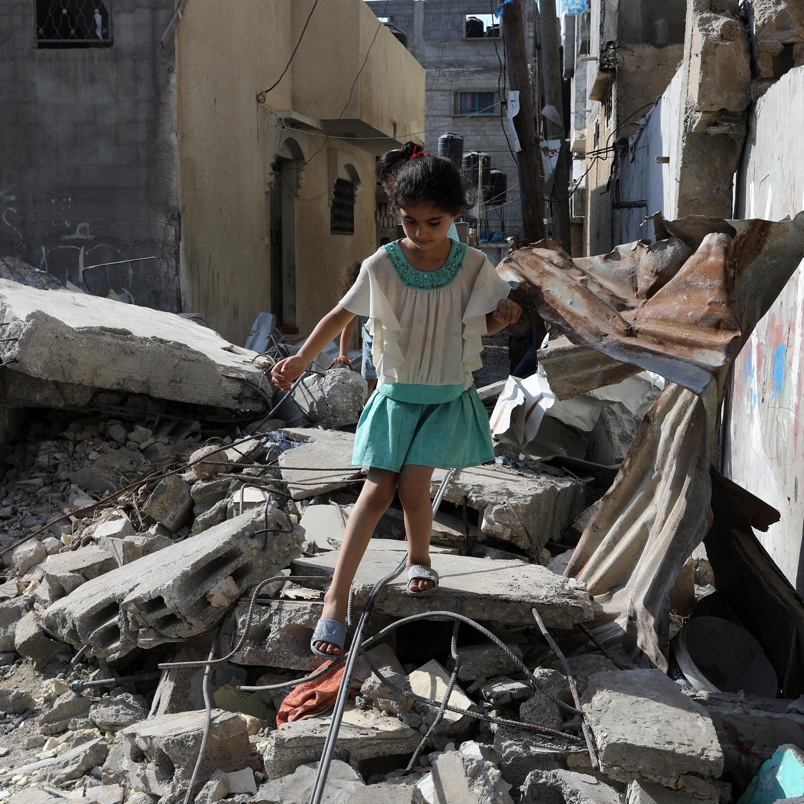 Une petite fille marche prudemment sur des gravats, dans une zone de conflit