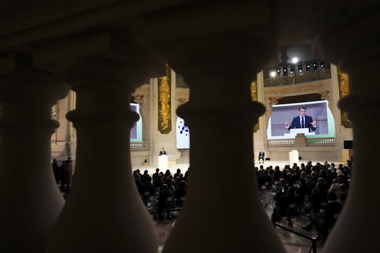 Un político desde la distancia y detrás de los pilares de piedra que lleva un discurso.