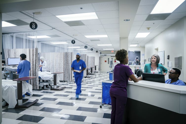 People in scrubs work and mill about in a hospital emergency room.