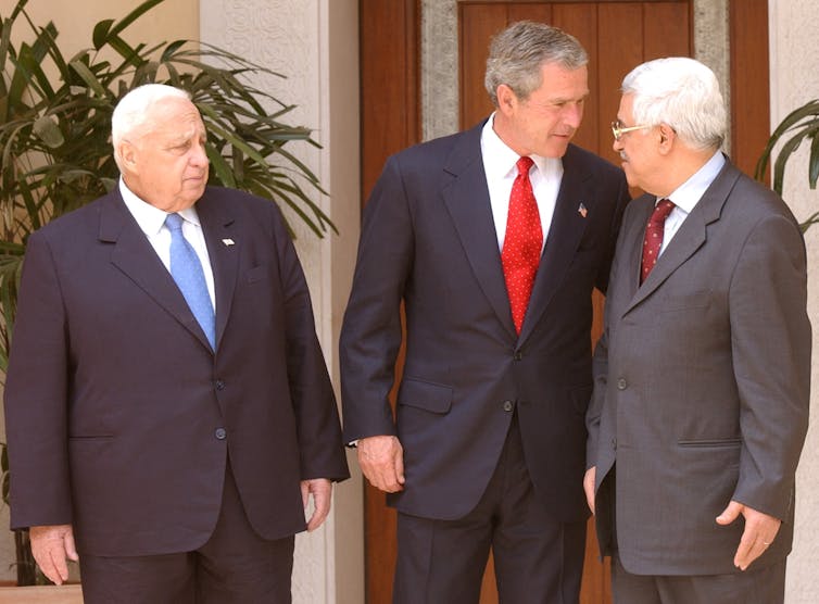 Three men in suits stand around