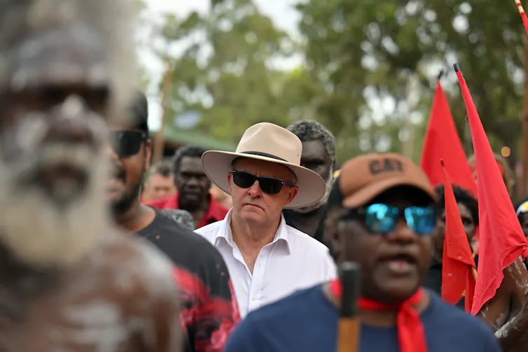 Anthony Albanese, wearing sunglasses and an Akubra, surrounded by First Nations people.