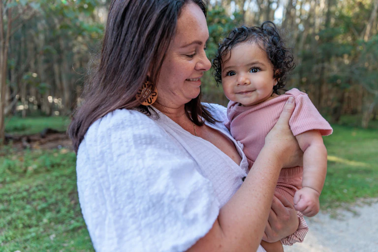 Indigenous Australian woman holding baby girl, outside