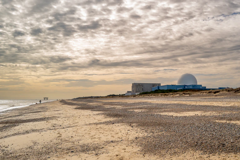 Beach landscape with nuclear plant on horizon.