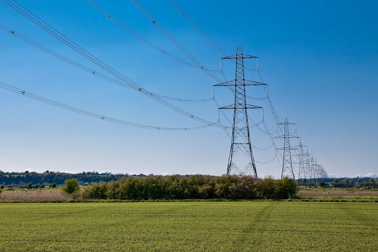 Row of large electricity pylons in flat british countryside