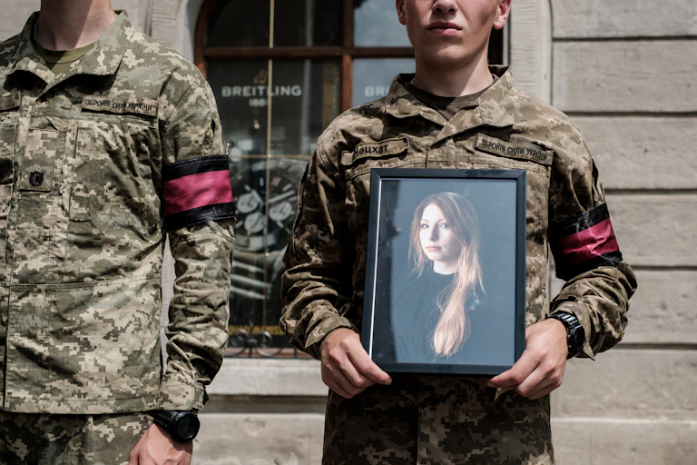 A soldier of the honor guard holds a portrait of the late Victoria Amelina.