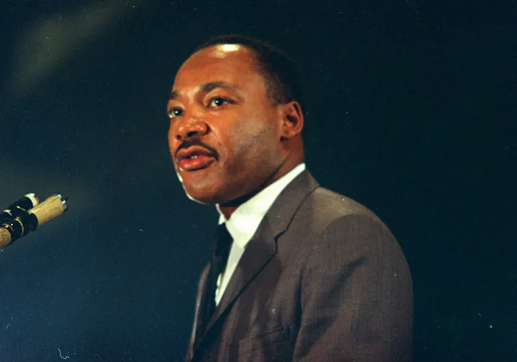 a man in a suit and tie stands in front of a microphone