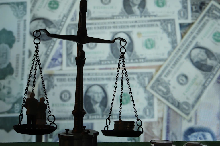 A photo illustration shows the scales of justice in silhouette in front of a backdrop made of dollar bills.