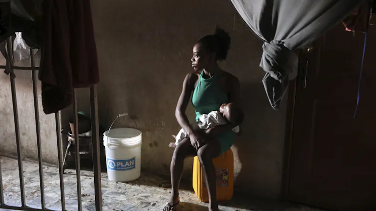 a woman sits on a yellow suitcase holding a baby