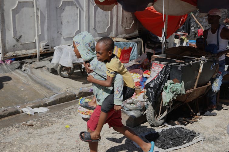 El niño que lleva una lápida usa un niño pequeño en la espalda