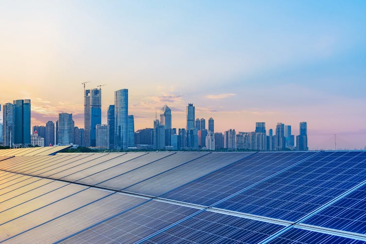 solar panels with a city skyline in the background.