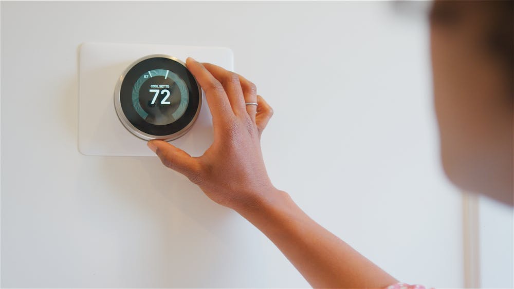 A person adjusting a digital thermostat.