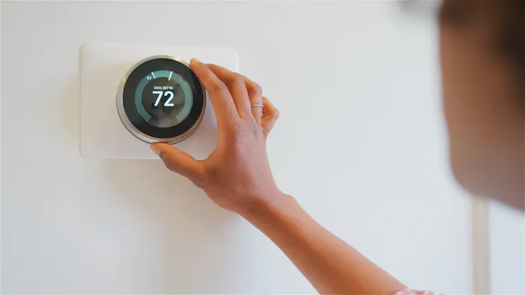a person adjusting a digital thermostat