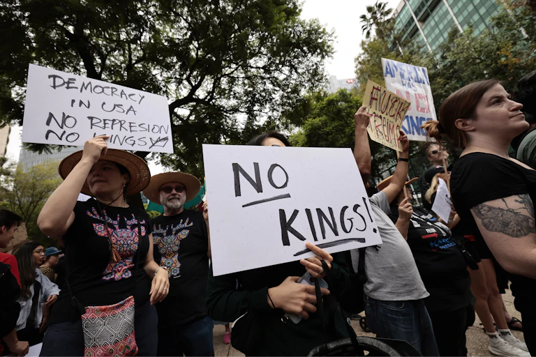 Protesters hold up signs saying no kings.
