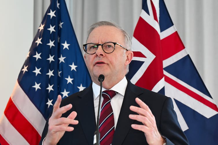 Anthony Albanese speaking to the media in from of the US and Australian flags.