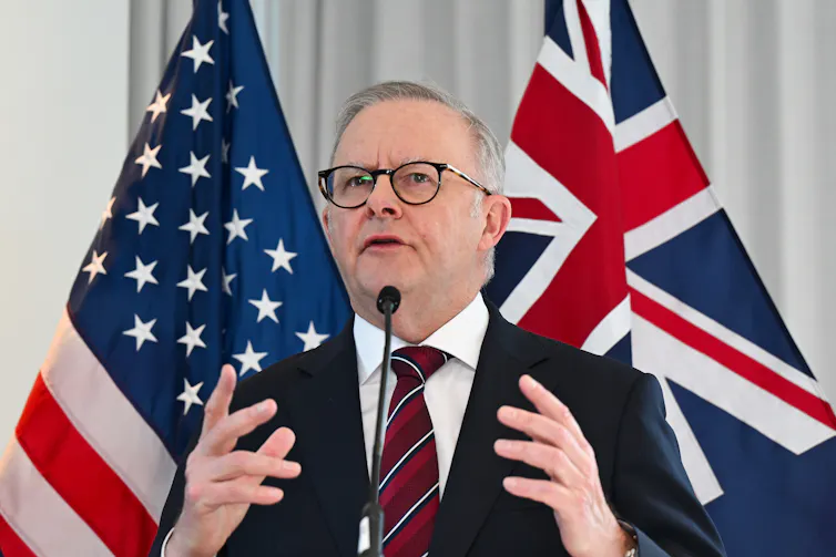Anthony Albanese speaking to the media in from of the US and Australian flags.