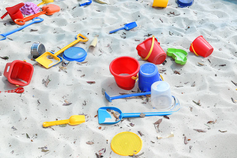 A sandpit dotted with plastic buckets and spades.