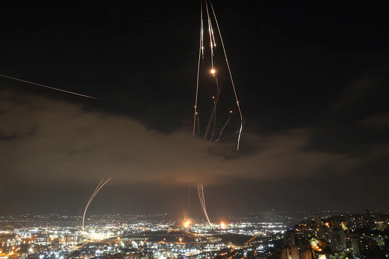 Night photo of streaks of light and explosions over a city.