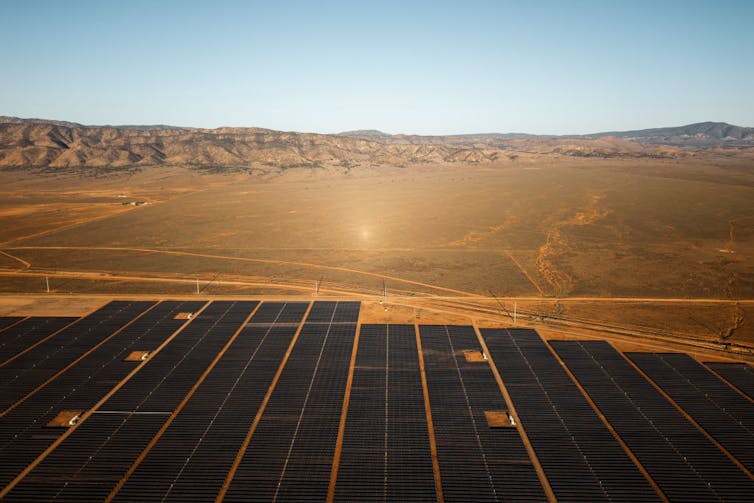 a solar farm in dry landscape with mountain backdrop