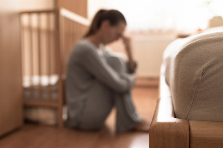Una mujer apesadumbrada junto a una cuna