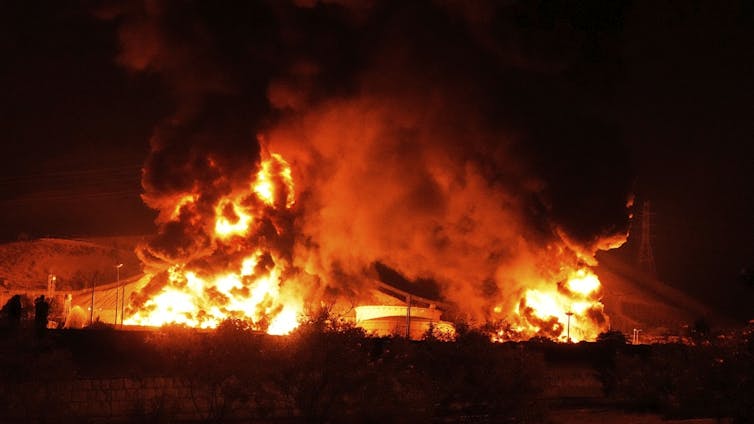 A facility engulfed in flames at night.