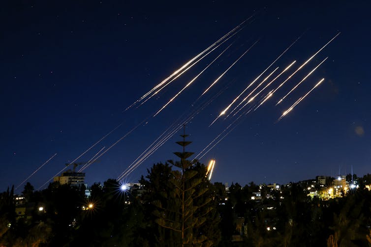 Streaks from missiles appear in the night sky.