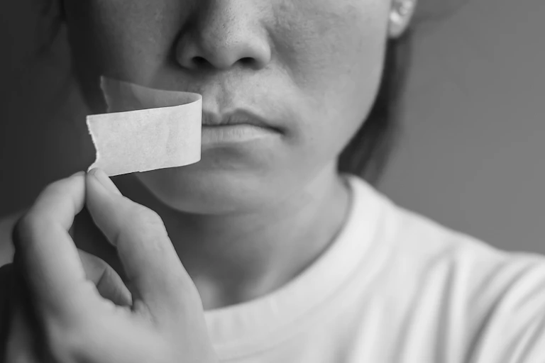 Woman peeling adhesive tape off her mouth