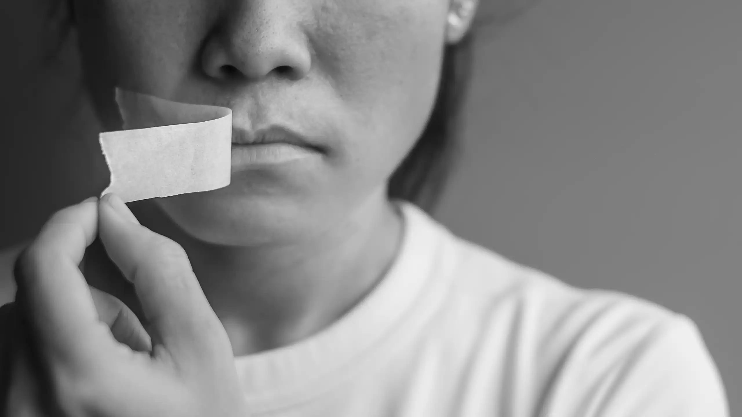 Woman peeling adhesive tape off her mouth