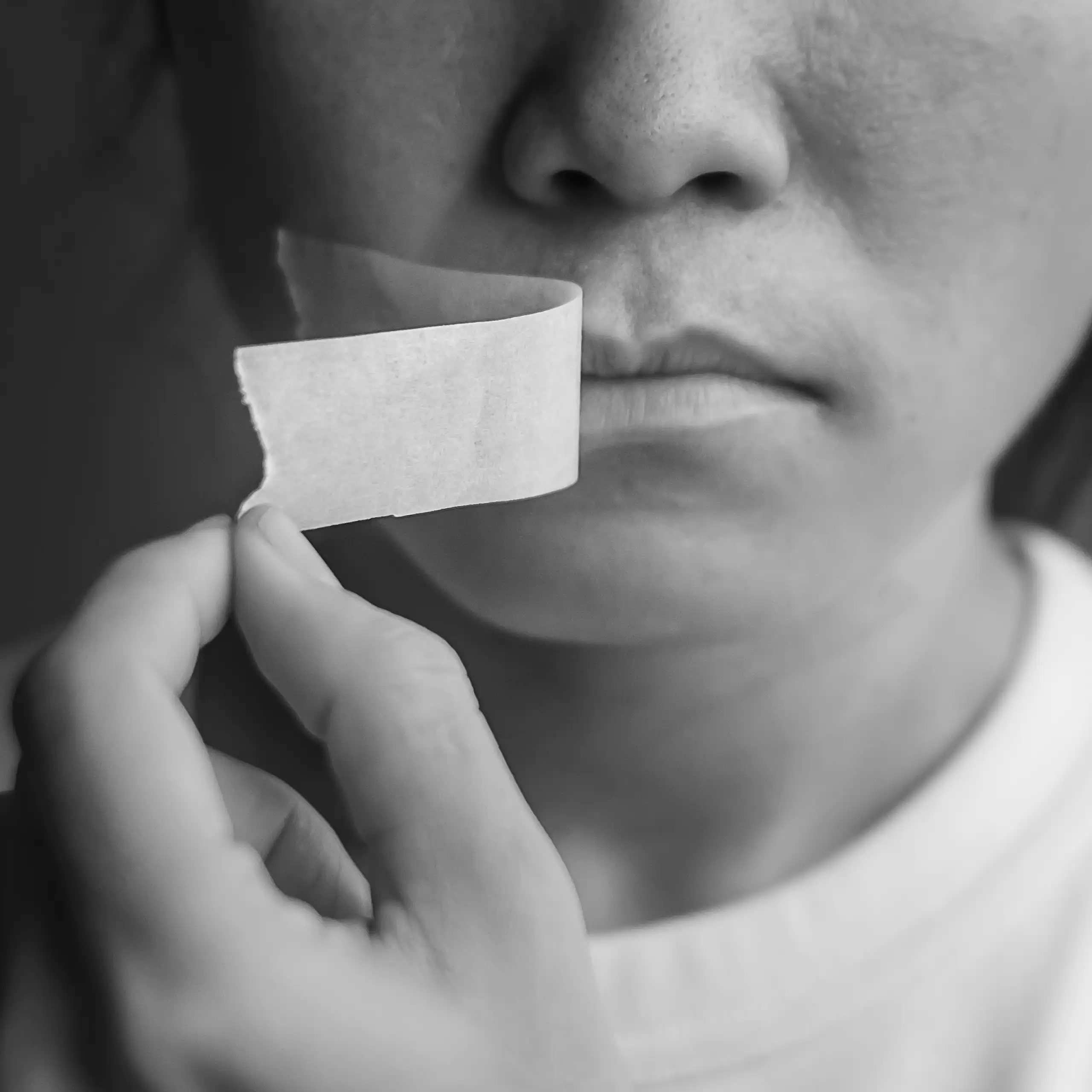 Woman peeling adhesive tape off her mouth