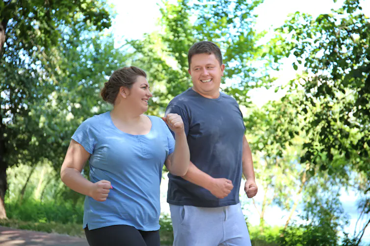 Man and woman running together in leafy park