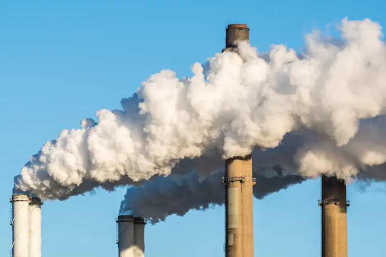 Power station smokestacks against a blue sky.