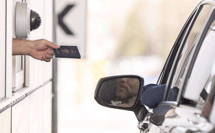 Se puede ver que el brazo que aparece desde el quiosco que pasa el pasaporte de regreso al automovilista.