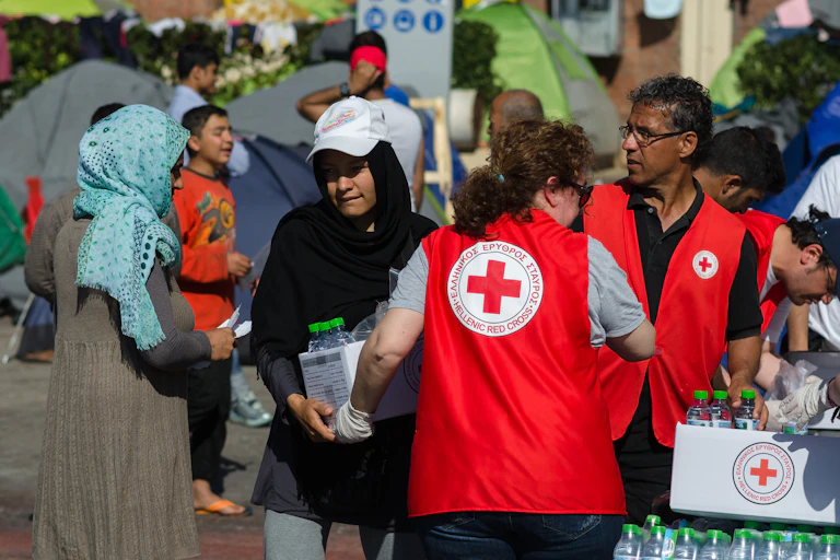 Aid workers from the Hellenic Red Cross distribute boxes of food and water for Syrian refugees in Athens in 2016