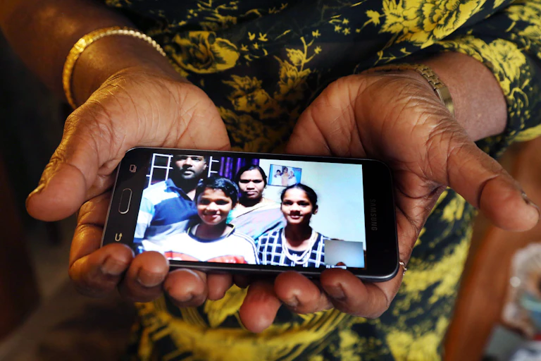 a pair of hands holds a phone which displays a photo of a family