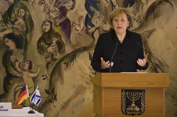 A woman dressed in black stands at a podium.