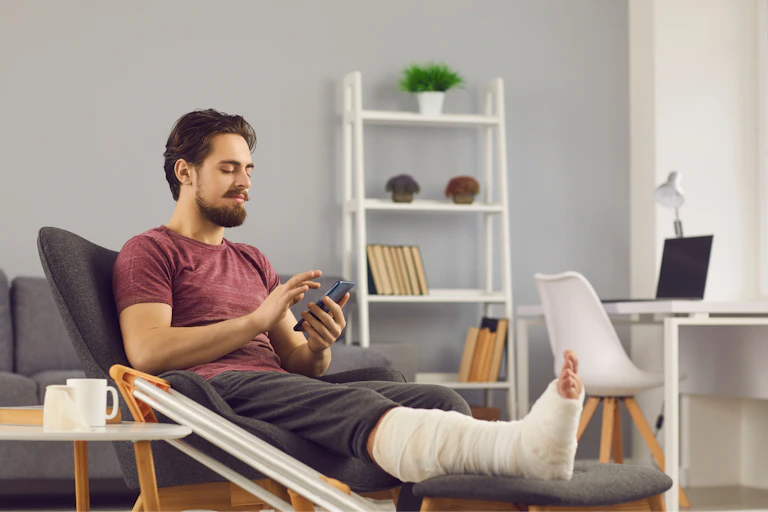 Man with foot and leg cast uses social media on mobile phone