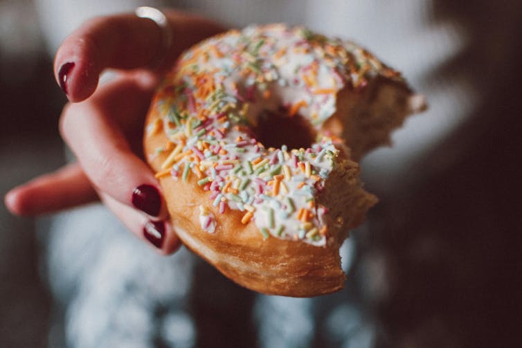 Woman holds doughnut with sprinkles