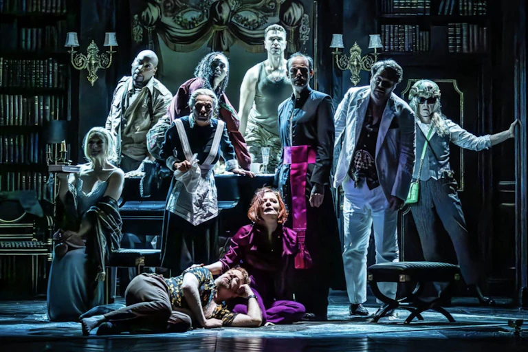 A group of actors on stage in various guises, male and female.