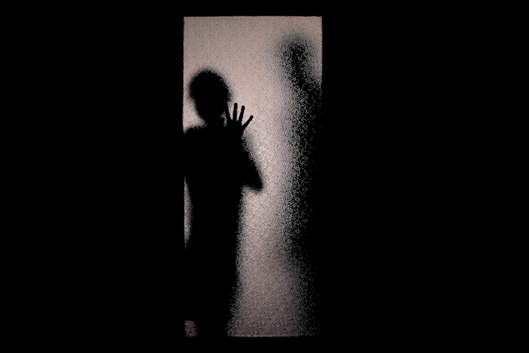 Silhouettes of two people behind glass door