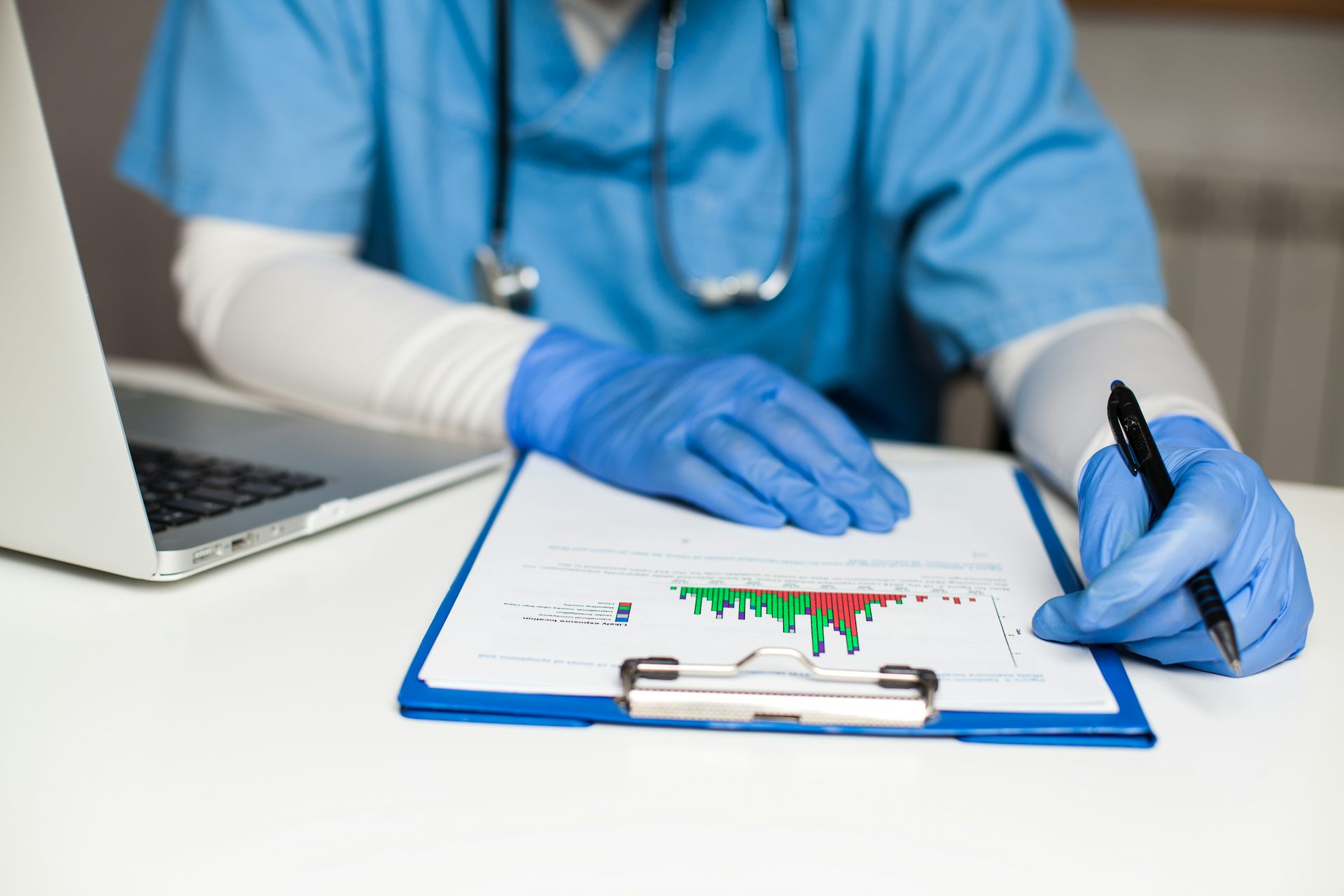 Une personne en habit médical tient un crayon et regarde un graphique