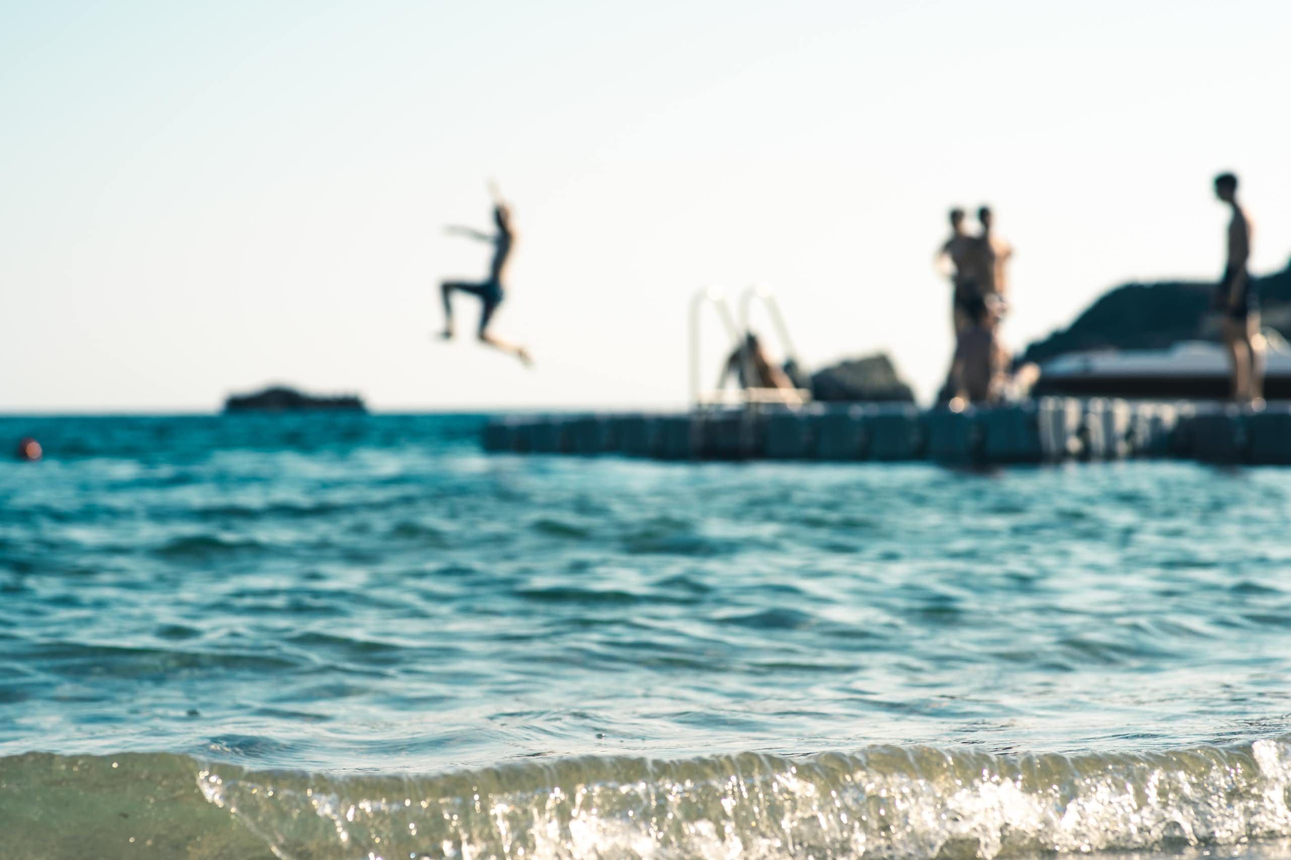 teens jumping into sea