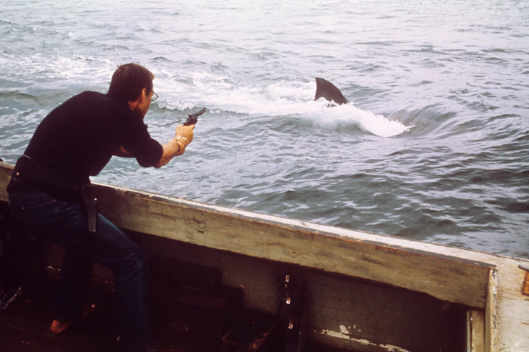 A 1070s US police officer shooting at a shark from a boat